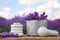 Spa stones, fresh lavender flowers and marble mortar on wooden table outdoors, closeup