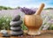 Spa stones, fresh lavender flowers and mortar on wooden table outdoors, closeup