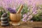 Spa stones, fresh lavender flowers and mortar on wooden table outdoors, closeup. Space for text