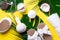 Spa tools: white towel, bamboo slippers, herbal ball, cream, wooden brush, coconut oil, monstera on yellow background. Cosmetic