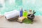Spa treatment set concept, massage oil with nature soap bar with white hand towel and wooden mortar over blurred blue water backgr