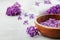 Spa and wellness composition with perfumed lilac flowers water in wooden bowl and terry towel on stone background, aromatherapy