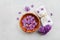 Spa and wellness composition with perfumed lilac flowers water in wooden bowl and towel on stone background, top view, flat lay