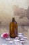 Spa and wellness concept: preparation of essential oil with pink roses, brown bottle of tincture on wooden board with a