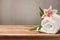 Spa and wellness concept with white towel and flower on wooden table over rustic grey background