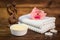 Spa or wellness set. Yellow sea salt in white bowl, candle, towels, brown wooden statuette and pink flowers lily on brown wooden