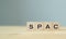 SPAC symbol. Wooden cubes with words SPAC, special purpose acquisition companies` on beautiful grey background, copy space. Inves