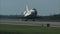 Space shuttle landing on runway and throws a parachute