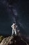 Spaceman standing on rocky mountain under starry sky.