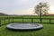 Spacious backyard with trampoline and wooden fence in evening