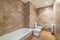 Spacious bathroom with beige brown tiles, bathroom with toilet and bidet. The concept of a stylish and simple renovation
