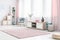 Spacious living room interior with wooden cabinet, grey elegant chair and fluffy pastel pink rug