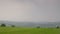 A spacious meadow, with a hiker passing by