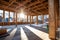 A spacious room featuring numerous windows and sturdy wooden beams throughout, A zero-energy building under construction using
