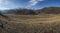 Spacious valley, snowy ridge and blue sky with white clouds