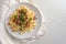 Spaetzle, homemade egg noodles with cheese, roasted bacon, onion and breadcrumbs, served with parsley garnish on a white painted