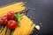 Spagetti, tomatoes and garlic on black background