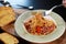 Spaghetti bacon with fork in hand and tomato in the green and white color plate and Garlic bread on wooden table background. Foods