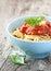 Spaghetti bolognese in blue bowl on vintage rustic wood