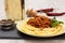 Spaghetti bolognese on a plate, spices and a bottle of wine