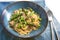 Spaghetti carbonara with green asparagus on a blue plate with napkin and cutlery, selected focus