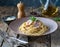 Spaghetti carbonara with ham and cheese in a plate on a black background. AI-generated image