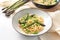 Spaghetti carbonara variation with green asparagus served in a plate, ingredients and napkin on a white table, copy space,