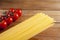 Spaghetti and cherry tomatoes on a wooden table. Spaghetti to the right of tomatoes. Homemade food or restaurant. Ingredients for