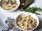 Spaghetti with clams, garlic and parsley in a white bowls, gold appliances on a gray background