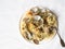 Spaghetti with clams, tomatoes, garlic and parsley on a white plate and rustic fork on a white background. Top view