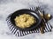 Spaghetti with green sauce in a black bowl, gold appliances on a gray background.