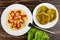 Spaghetti with ketchup in plate, fork, vegetable cutlets in plate, leaves of lettuce on wooden table. Top view