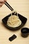 Spaghetti macaroni in black ceramic plate with chopsticks at bamboo mat