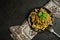 Spaghetti with meat mushroom sauce on a plate with a kitchen towel, fork and peppercorns on a black concrete background. top view