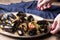 Spaghetti with mussels, tomatoes in spicy sauce in an original plate on an old wooden table. Mollusks Mytilus close up.