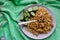 Spaghetti pasta with melted hard cheese and fresh cucumbers on a cloth, homemade food on a plate, large portion, culinary cuisine