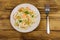 Spaghetti pasta with prawns, green olives and parsley on wooden table. Top view