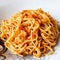 Spaghetti with red pesto sauce and crispy pork