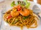 The Spaghetti, Shrimp fried peppers on a white plate. on the wooden table.