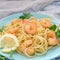 Spaghetti with shrimps on blue plates. A nice delicious dinner, decorated with parsley and lemon.
