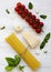 Spaghetti, tomatoes, basil, parmesan, garlic. Ingredients for cooking pasta on a white wooden background, flat lay. From above