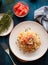 Spaghetti with tomatoes and thyme in a plate on a blue table. T