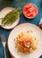 Spaghetti with tomatoes and thyme in a plate on a blue table. T