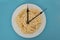 Spaghetti on a white plate, on blue  background, and clock tongues