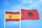 Spain and Albania two flags on flagpoles and blue cloudy sky