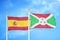 Spain and Burundi two flags on flagpoles and blue cloudy sky