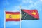 Spain and Papua New Guinea two flags on flagpoles and blue cloudy sky