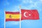Spain and Turkey two flags on flagpoles and blue cloudy sky