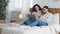 Spaniard arab married couple man and woman lying on bed in cozy bedroom home using laptop for video call making internet