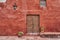 spanish colonial building with rich red color on the facade and an antique wooden door with ornaments